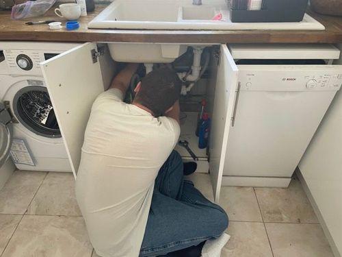 man-fixing-pipes-under-sink